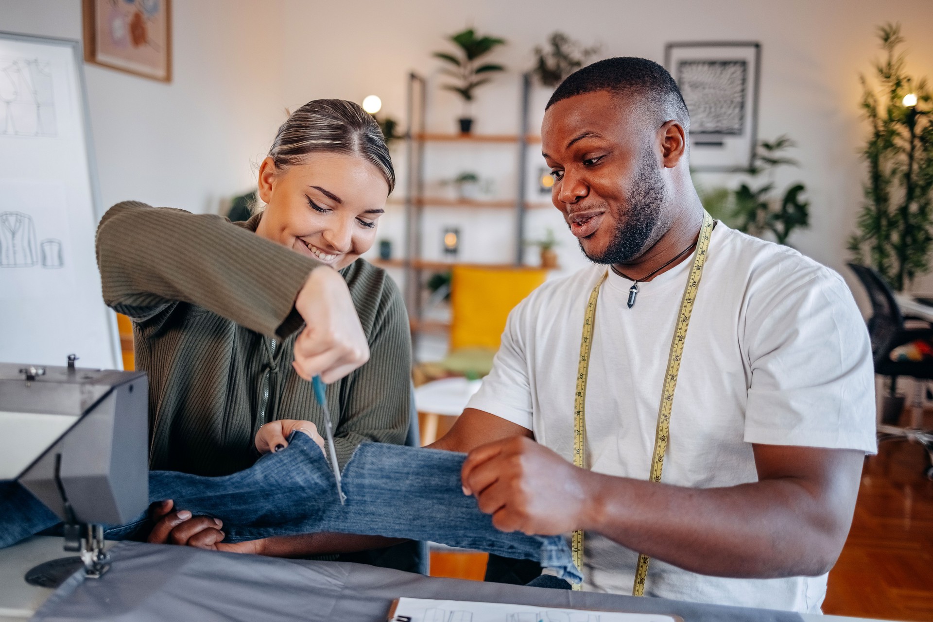 People trying to fix some clothes at home using sewing machine and using scissors for cutting