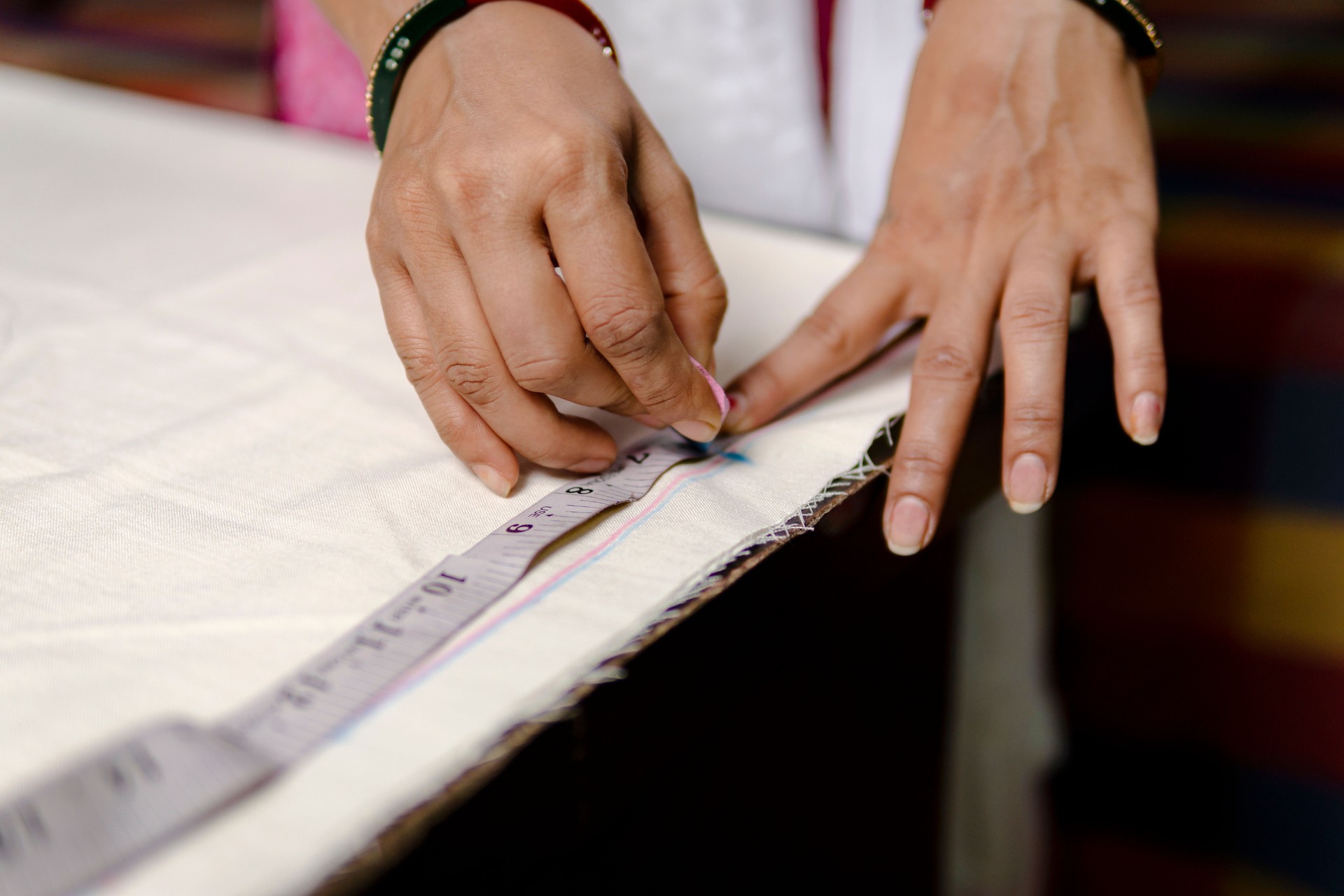 Tailor woman is measuring clothes with inch tape.