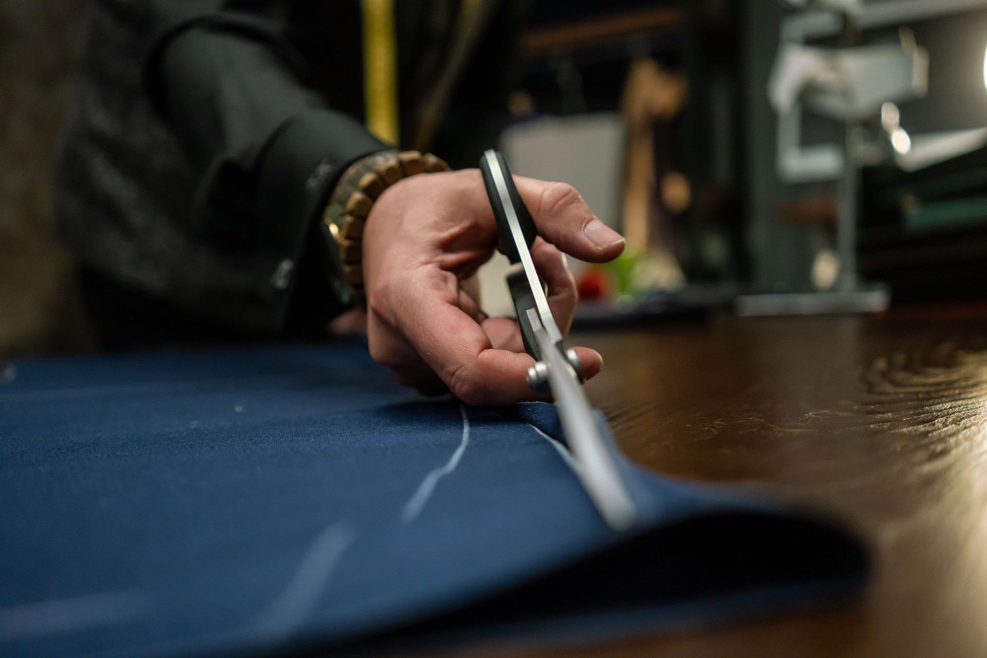 man fashion designer is cutting fabric in his studio horizontal working with hands close up still